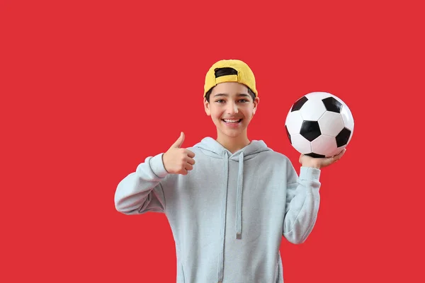 Malý Chlapec Fotbalovým Míčkem Ukazující Palec Nahoru Červeném Pozadí — Stock fotografie