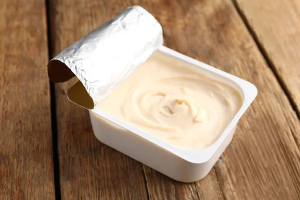 木制底座上有美味奶油乳酪的塑料容器 — 图库照片