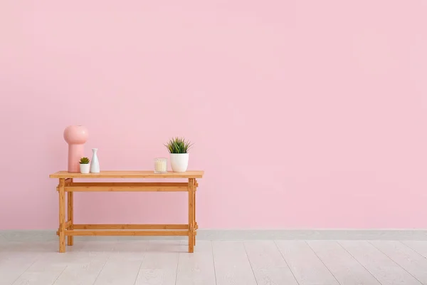 Деревянный Стол Комнатными Растениями Вазами Свечами Возле Розовой Стены — стоковое фото