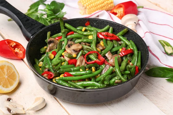 stock image Frying pan with different vegetables on light wooden background