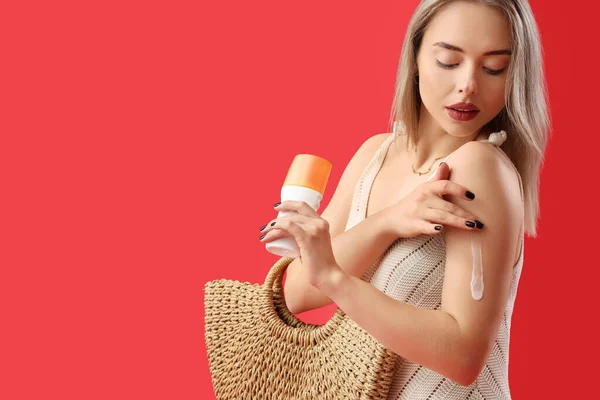 Young Woman Applying Sunscreen Cream Red Background — Stock Photo, Image