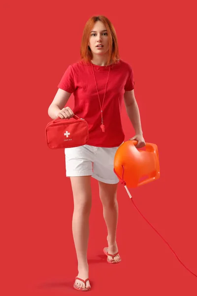 Γυναικείος Ναυαγοσώστης Σημαδούρα Διάσωσης Και Κουτί Πρώτων Βοηθειών Κόκκινο Φόντο — Φωτογραφία Αρχείου