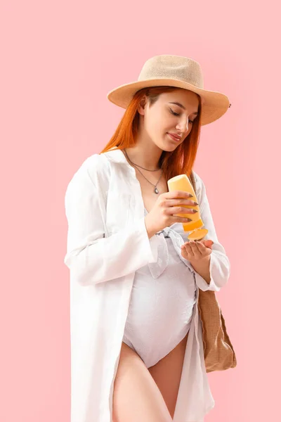 Jonge Zwangere Vrouw Aanbrengen Zonnebrandcrème Roze Achtergrond — Stockfoto