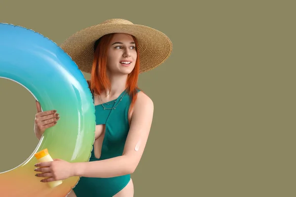 日焼け止めクリームと緑の背景にインフレータブルリングを持つ若い女性 — ストック写真