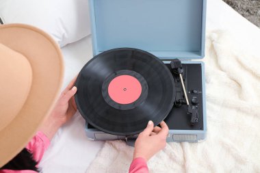 Yatak odasında vinil diski ve pikabı olan genç bir kadın, yakın plan.