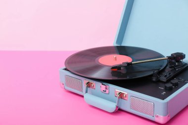 Pembe duvarın yanındaki masada vinil diski olan kayıt çalar.