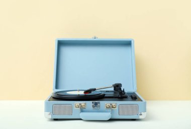 Bej duvarın yanındaki masada vinil diski olan kayıt çalar