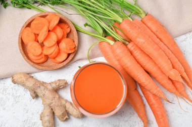 Beyaz arkaplanda iki bardak taze havuç suyu ve zencefil.