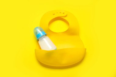 Sarı arka planda önlüklü bir şişe süt.