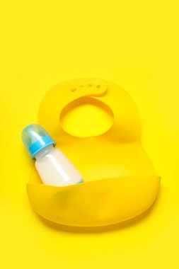 Sarı arka planda önlüklü bir şişe süt.