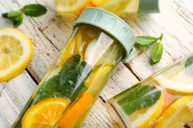 Beyaz ahşap arka planda limonlu ve naneli spor şişeleri