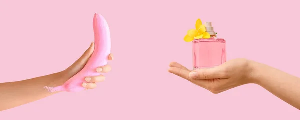 stock image Female hands with natural manicure, painted banana and perfume bottle on pink background. Banner for design