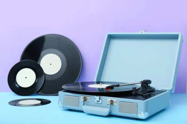 ライラック壁の近くのテーブルの上にビニールディスクを持つレコードプレーヤー — ストック写真