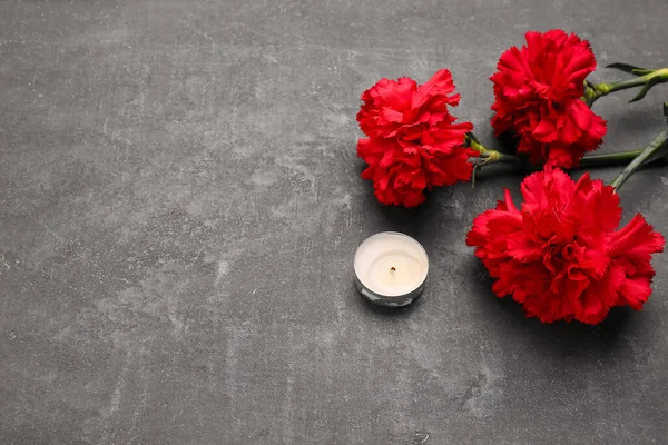 Rote Nelken Und Kerze Auf Dunklem Grunge Hintergrund — Stockfoto