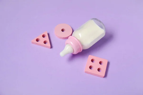 Butelka Mleka Dla Dziecka Zabawkami Tle Liliowym — Zdjęcie stockowe