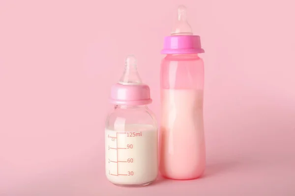 stock image Bottles of milk for baby on pink background