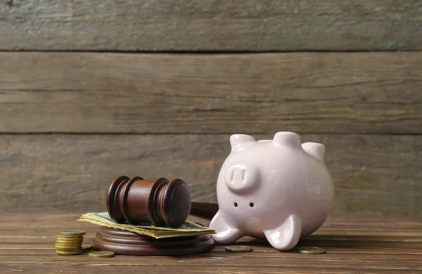 茶色の木製の背景に裁判官のギャベルとお金を持つ貯金箱 破産の概念 — ストック写真
