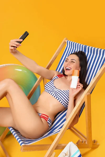 Young Woman Sunscreen Cream Taking Selfie Deck Chair Yellow Background — Stock Photo, Image