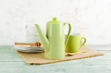 Yeşil ahşap masa üzerinde şık çay seti olan hasır bir hasır.