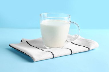 Mavi zemin üzerinde taze süt olan cam bardak.