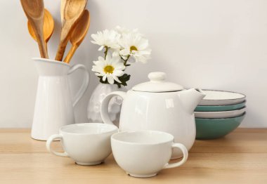 Güzel çay takımları, çiçekler ve ahşap masada farklı mutfak malzemeleri.