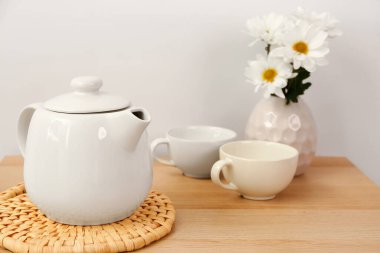 Hasır hasırlı çay seti ve ahşap masada çiçekler.