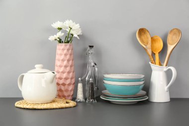 Çiçekli çaydanlık ve siyah masada farklı mutfak malzemeleri.