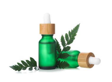 Beyaz arka planda bitki dallı kozmetik yağı şişeleri