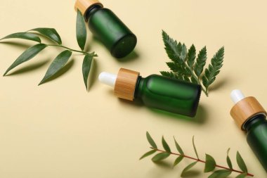 Bej arka planda bitki dalları olan kozmetik yağı şişeleri