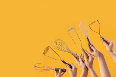 Sarı arka planda farklı çırpı ve eziciler tutan kadın eller.