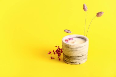 Sarı arka planda mumlu ve çiçekli tutucu
