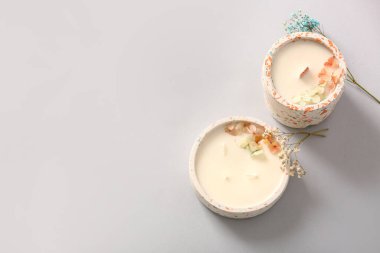 Gri arka planda mumları ve çiçekleri olan tutucular