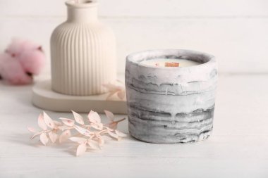 Beyaz ahşap zemin üzerinde mum ve kamış ayırıcı ile tutucu