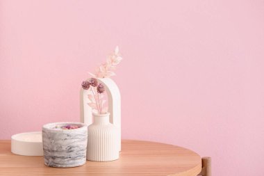 Odadaki pembe duvarın yanındaki masada elinde mumlar ve dekor olan tutucular.