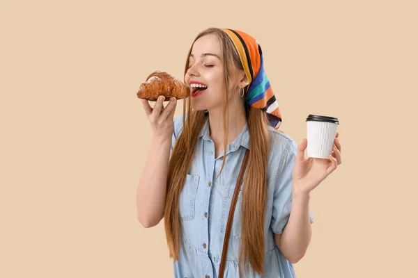 Young Woman Cup Coffee Eating Croissant Beige Background — Zdjęcie stockowe