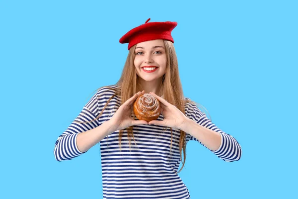 Young Woman Beret Tasty Bun Blue Background — Stock Photo, Image