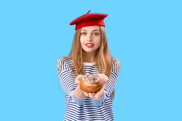 Young Woman Beret Tasty Bun Blue Background — Stock Photo, Image