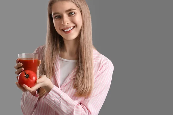 野菜ジュースとトマトのガラスを持つ若い女性が灰色の背景に — ストック写真