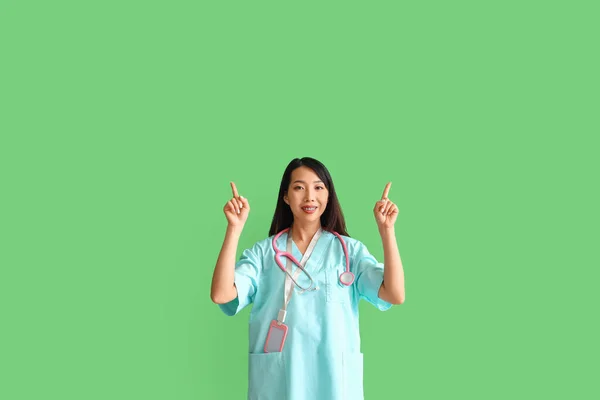 Asiatische Medizinpraktikantin Zeigt Auf Etwas Auf Grünem Hintergrund — Stockfoto