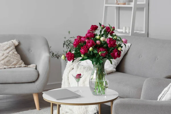 リビングルームのコーヒーテーブルの上に赤い牡丹 ガラス ラップトップ付き花瓶 — ストック写真