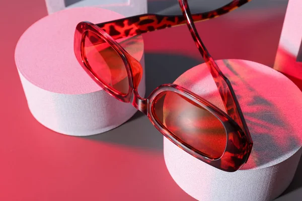 Podien Mit Stylischer Sonnenbrille Auf Rotem Hintergrund — Stockfoto