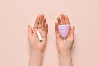 Adet bardağı ve pembe arka planda tamponu olan bir kadın.