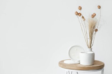 Odadaki ışık duvarının yanındaki masada kurumuş çiçekler ve mumlar.