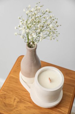 Odadaki ışık duvarının yanındaki sandalyede çingene çiçekleri ve mum, yakın plan.