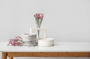 Odadaki ışık duvarının yanındaki masada güzel çiçekler ve mumlar.