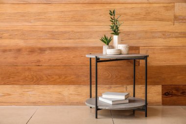 Çiçekler, mumlar ve kitaplar odasındaki ahşap duvarın yanındaki masada.