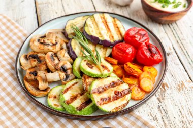 Izgara sebzeli tabak ve beyaz ahşap arka planda ekşi krema.