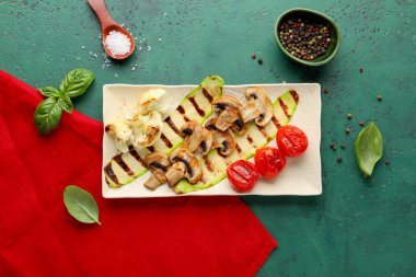 Izgara sebzeli tabak ve yeşil arka planda fesleğen.