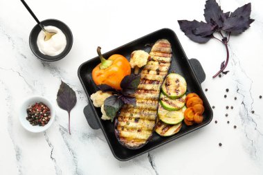 Beyaz arka planda ızgara sebzeli fırın ve fesleğen.