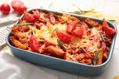 Beyaz fayanslı domates soslu ve peynirli makarna kabı.